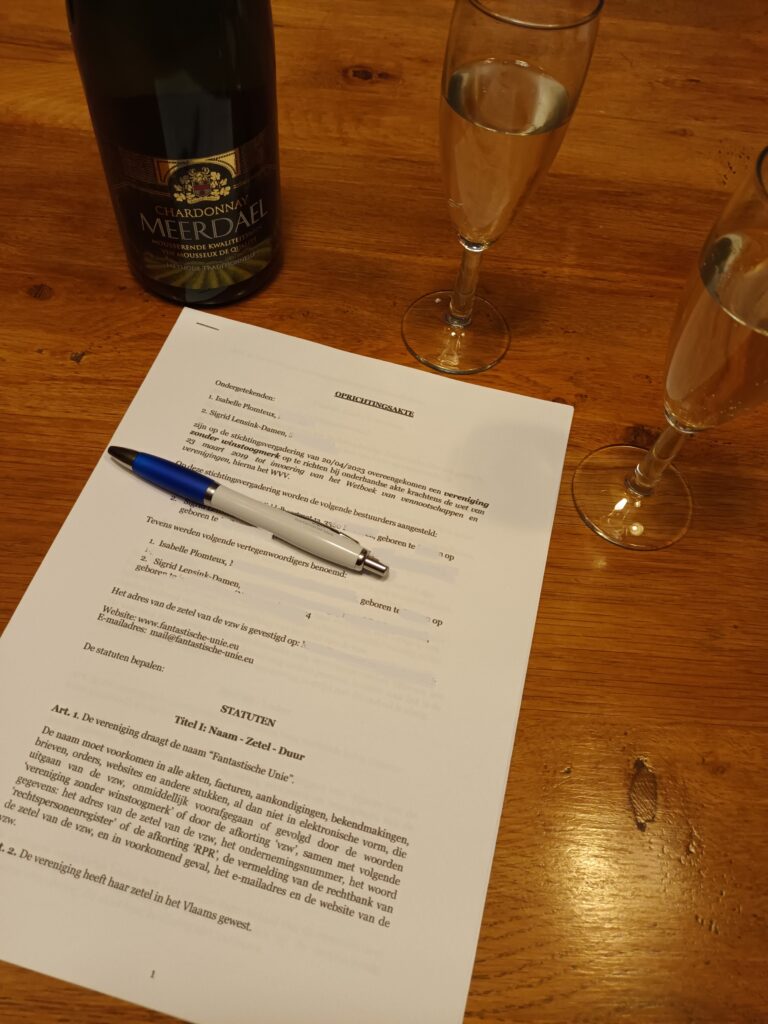 Fles champagne en twee glazen boven een blad papier met een pen erop.