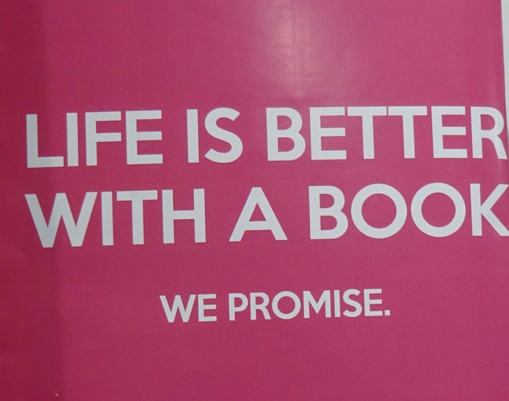 Roze achtergrond met tekst Life is better with a book. We promise.