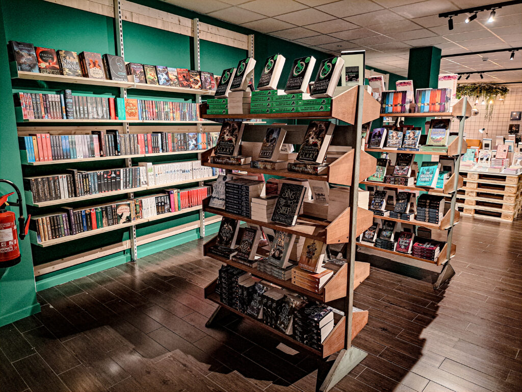 Boekwinkel met groene wand, boeken in losstaande boekenrekken en tegen de wand