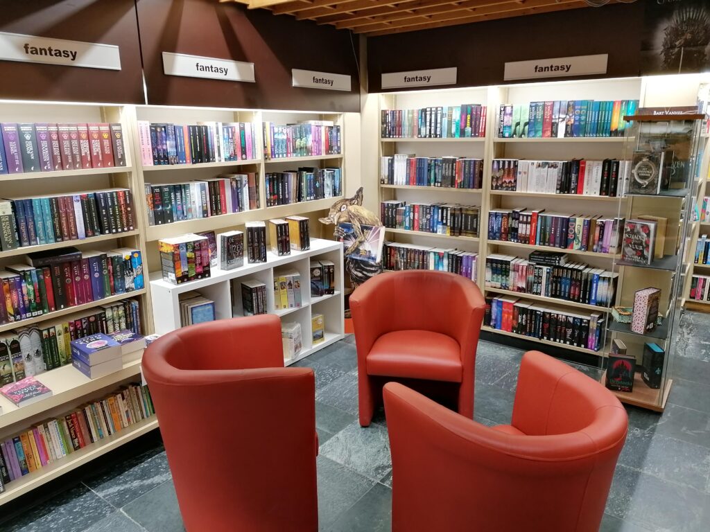 boekenkasten in een hoek opgesteld met ervoor een zitje met rode fauteuils